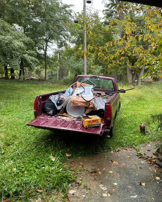 Loaded maroon pickup truck parked on a lawn beside a driveway